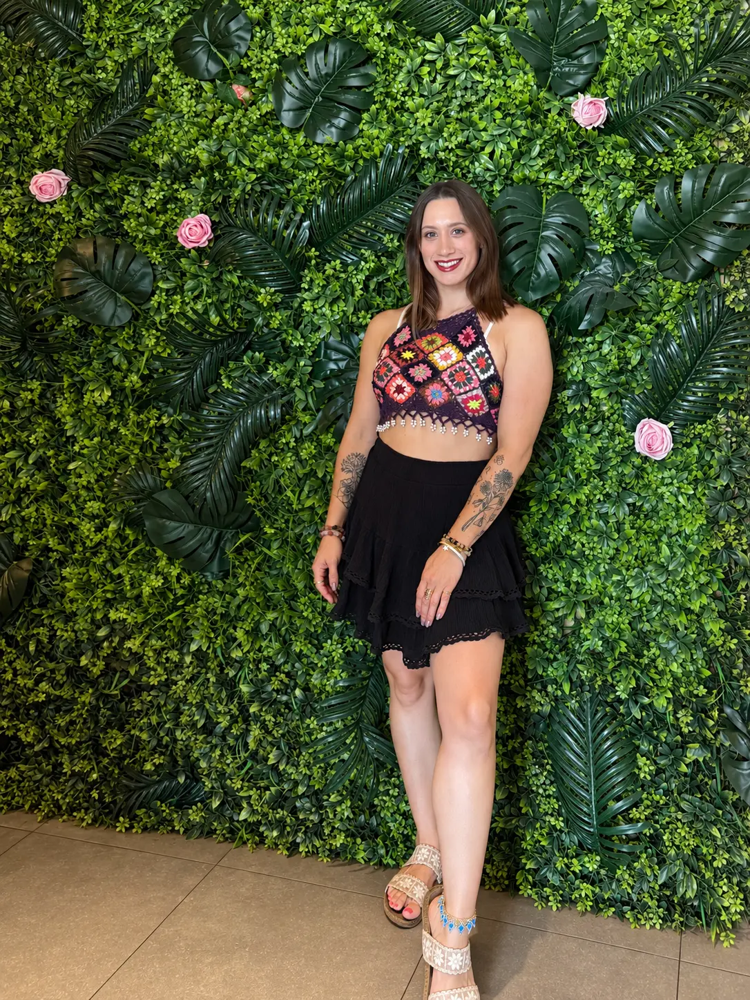 Kayla smiling in front of a lush green plant wall